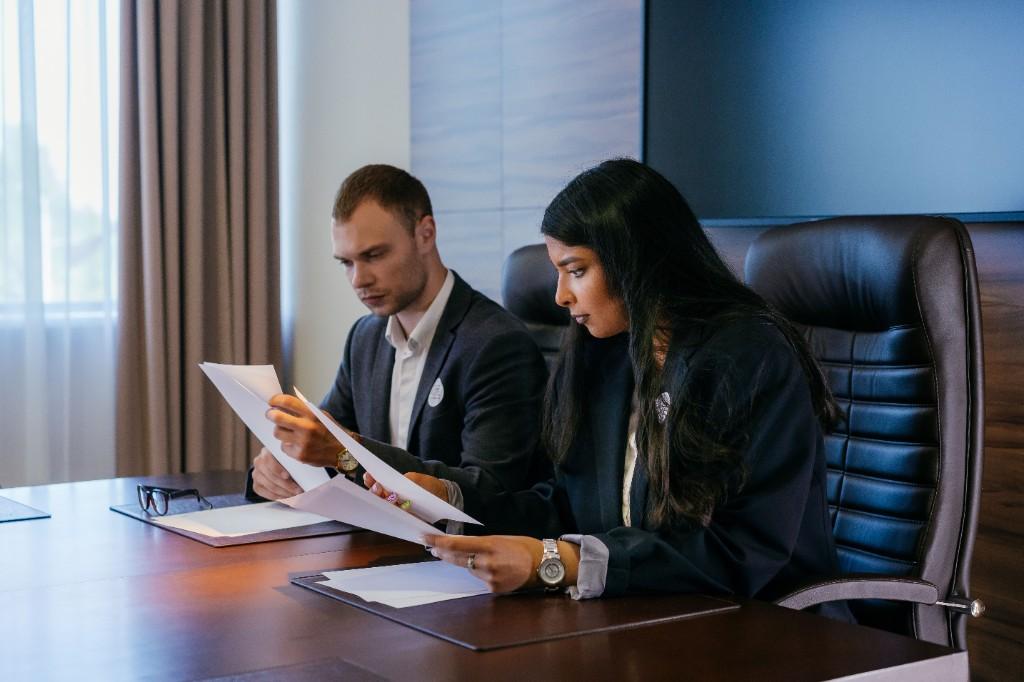 Two professionals reviewing documents side by side at a conference table